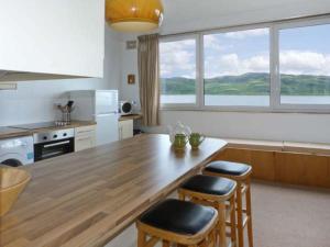a kitchen with a large wooden table and stools at Top Flat in Tighnabruaich