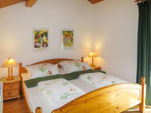 um quarto com uma cama de madeira e lençóis brancos em Holiday Home Fischer by Interhome em Lechbruck