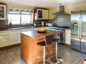 a kitchen with a wooden island with two bar stools at Schoolhill Croft in Collieston