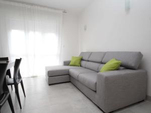 un soggiorno con divano grigio e cuscini verdi di Casa Sandra a Rosolina Mare