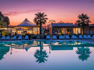 a resort pool with chairs and a gazebo at Holiday Home Cecina Mare-11 by Interhome in Marina di Cecina