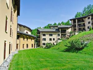 a building with a grassy yard next to some buildings at Apartment Residenza Chesa Margun 58-5 by Interhome in Surlej