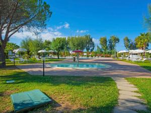 einen Park mit einem Pool, Tischen und Sonnenschirmen in der Unterkunft Holiday Home Cecina Mare-3 by Interhome in Marina di Cecina