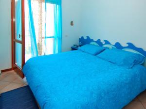 ein blaues Bett in einem Schlafzimmer mit einem Fenster in der Unterkunft Holiday Home Mediterraneo-2 by Interhome in Rosolina Mare