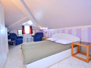 a bedroom with a large bed and blue chairs at Apartment Ivana-5 by Interhome in Raslina