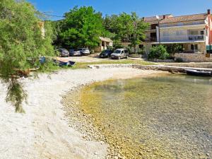 a beach with cars parked in front of a building at Apartment Šarenko-3 by Interhome in Vela Luka