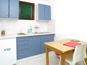 cocina con armarios azules y mesa de madera en Apartment Šarenko-5 by Interhome, en Vela Luka