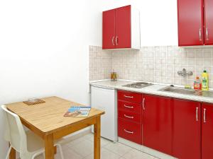 a kitchen with red cabinets and a wooden table at Apartment Šarenko-4 by Interhome in Vela Luka