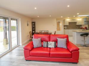 a red couch in a living room with a kitchen at The Donkey Shed in Sherborne