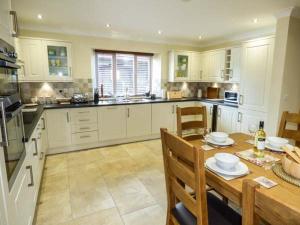 a kitchen with white cabinets and a wooden table at Ty Buddug in Llandegla