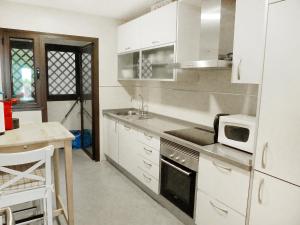 cocina con armarios blancos, fregadero y microondas en Apartment Mirador de la Yesera by Interhome, en Santa Fe de los Boliches