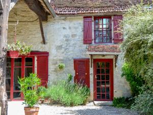 TanlayにあるHoliday Home Chez Milou by Interhomeの赤い窓と赤いシャッターのある古い家