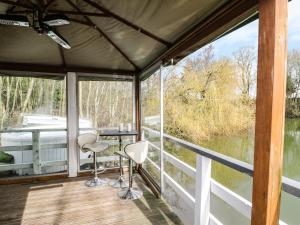 una veranda riparata con tavolo e sedie su una barca di The Lakeside Yurt a Tewkesbury