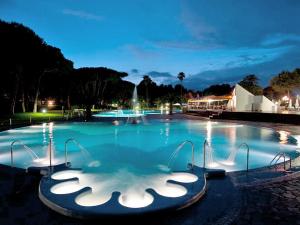 a large swimming pool at night with a fountain at Holiday Home Maxi Caravan Capri by Interhome in Baia Domizia