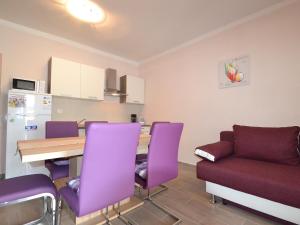 una cucina con sedie viola, tavolo e divano di Apartment Ana-2 by Interhome a Anić