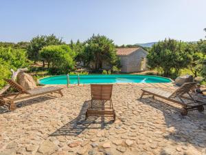 una piscina con due sedie e un tavolo di Holiday Home Mare di Ginepri - BAD115 by Interhome a Badesi