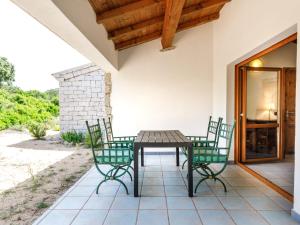 eine Terrasse mit einem Holztisch und 4 Stühlen in der Unterkunft Holiday Home Mare di Ginepri - BAD115 by Interhome in Badesi