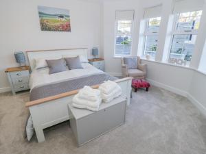 a bedroom with a bed and a chair and windows at Hafan Traeth Beach Haven in Benllech