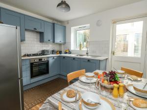 uma cozinha com armários azuis e uma mesa com comida em Little Tern em Weymouth
