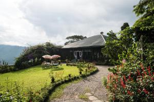 Casa con jardín con sillas y sombrillas en Singtom Tea Resort, en Darjeeling