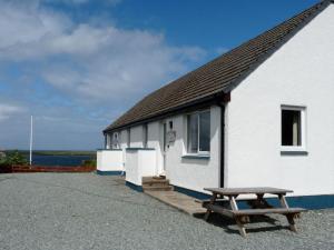 a white building with a bench in front of it at Holiday Home Alan's House by Interhome in Staffin +33 photos