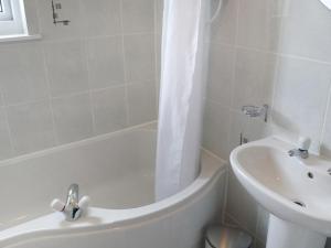 a white bathroom with a tub and a sink at Holiday Home Alan's House by Interhome in Staffin