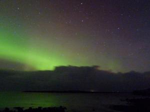an aurora in the sky over a body of water at Holiday Home Alan's House by Interhome in Staffin