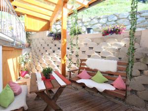 eine Terrasse mit einer Bank und einem Tisch mit Kissen in der Unterkunft Apartment Anita-2 by Interhome in Zellberg