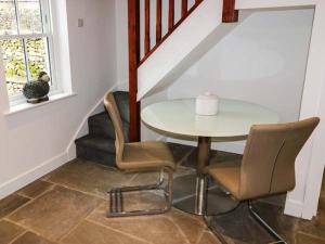 a table and chairs in a room with a staircase at 1 Primitive Croft in Chelmorton