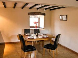 a dining room with a wooden table and black chairs at Stabal-y-Gwedd in Llanddulas