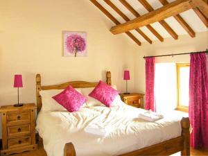 a bedroom with a bed with pink pillows and a window at Stabal-y-Gwedd in Llanddulas
