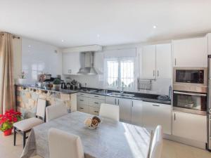 a kitchen with a table and chairs and a kitchen with white cabinets at Holiday Home Emballia by Interhome in Caulés