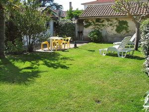 a yard with chairs and a table in the grass at Holiday Home La Poste by Interhome in Mimizan-Plage