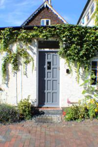 a white house with a blue door and ivy at Holiday Home Goudhurst by Interhome in Marden