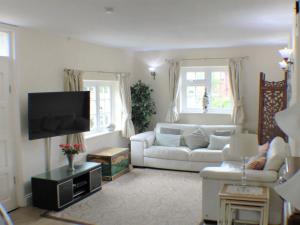 a living room with a white couch and a tv at Holiday Home Goudhurst by Interhome in Marden
