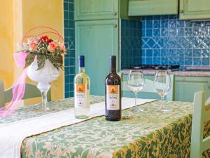 オロゼーイにあるApartment Gli Ontani trilo - ORO102 by Interhomeのワイン2本(テーブルとグラスの上に座る)