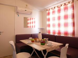 een eetkamer met een tafel en een bank bij Holiday Home Camping Thurium by Interhome in Marina di Schiavonea