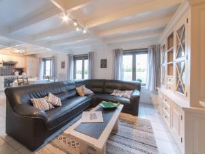 a living room with a black leather couch and a table at Holiday Home New Village Park-3 by Interhome in Bredene