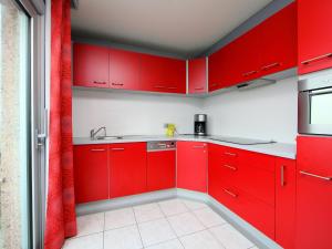 een rode keuken met witte toonbanken en rode kasten bij Apartment Residentie Astrid-5 by Interhome in Bredene