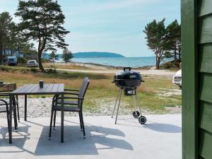 una parrilla sentada en una mesa junto a una mesa con sillas en Holiday Home Nesholmen - FJS127 by Interhome, en Leirvik