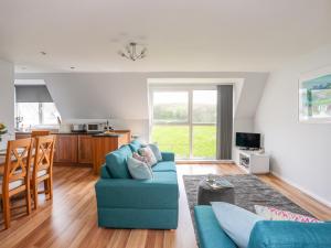 a living room with a blue couch and a kitchen at Isallt Cove in Trearddur