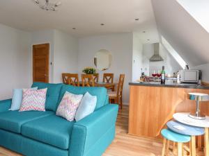 a living room with a blue couch and a kitchen at Isallt Cove in Trearddur