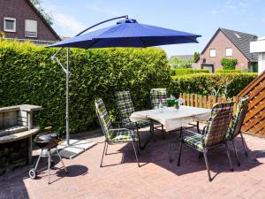 - une table et des chaises avec un parasol sur la terrasse dans l'établissement Holiday Home Entenkoje by Interhome, à Dornum