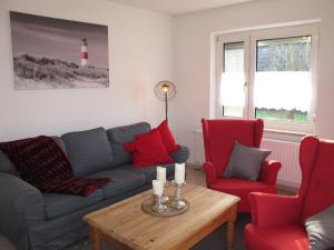 uma sala de estar com um sofá e duas cadeiras e uma mesa em Holiday Home Entenkoje by Interhome em Dornum