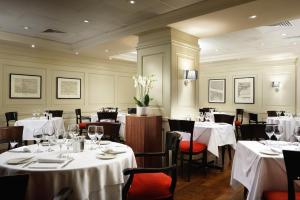 a restaurant with tables and chairs with white tablecloths at London Bridge Hotel in London