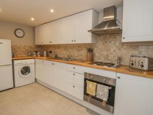 a kitchen with white cabinets and a washer and dryer at Hare Cottage in Market Rasen