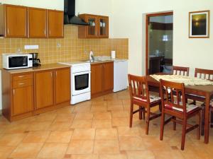 a kitchen with wooden cabinets and a table with chairs at Holiday Home Brigi by Interhome in Balatonszárszó