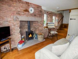 a living room with a brick wall with a fireplace at Rose Cottage in Monmouth