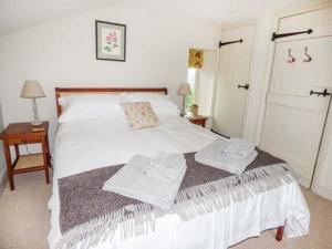 a bedroom with a white bed with two towels on it at Rose Cottage in Monmouth
