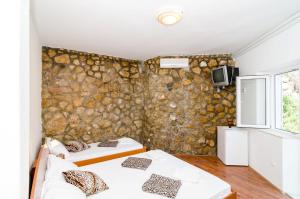 two beds in a room with a stone wall at Guest House Daniela in Mlini